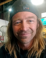 Artist Sun McColgin with long straight, dirty blonde hair, wearing a baseball cap backwards, with warm blue eyes and a closed smile